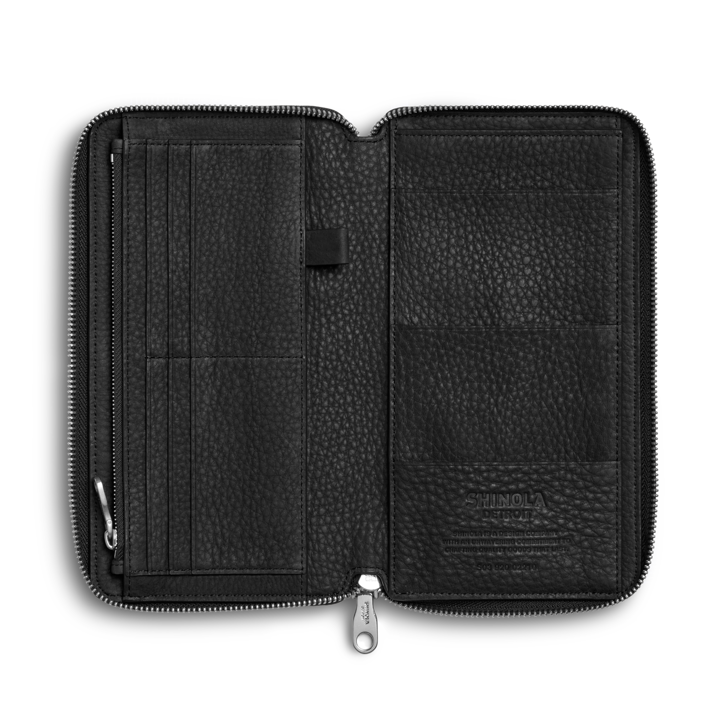 The Shinola Organizer Wallet - Black is an open Natural Grain Leather zippered travel wallet with multiple left card slots, a center pen loop, and embossed branding on the lower right interior. Shown empty against a white background.