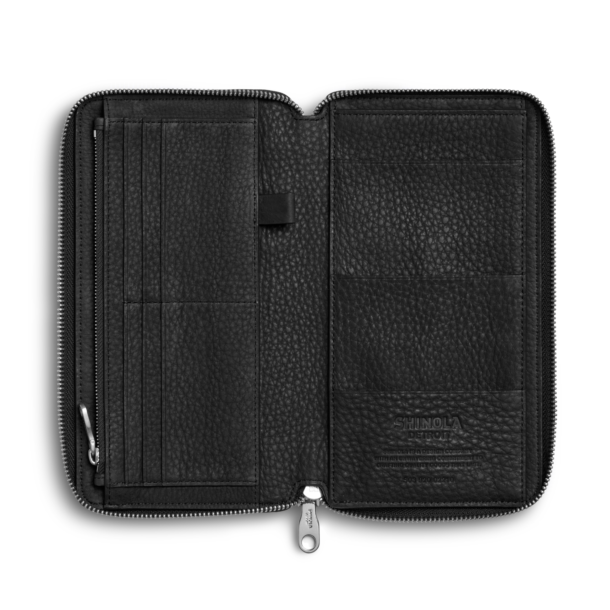 The Shinola Organizer Wallet - Black is an open Natural Grain Leather zippered travel wallet with multiple left card slots, a center pen loop, and embossed branding on the lower right interior. Shown empty against a white background.