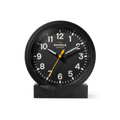 The Shinola 6" Runwell Clock features a black analog face with white numerals, white hour and minute hands, and a yellow second hand. It sits on an oak stand, highlighting Shinola craftsmanship against a white background.