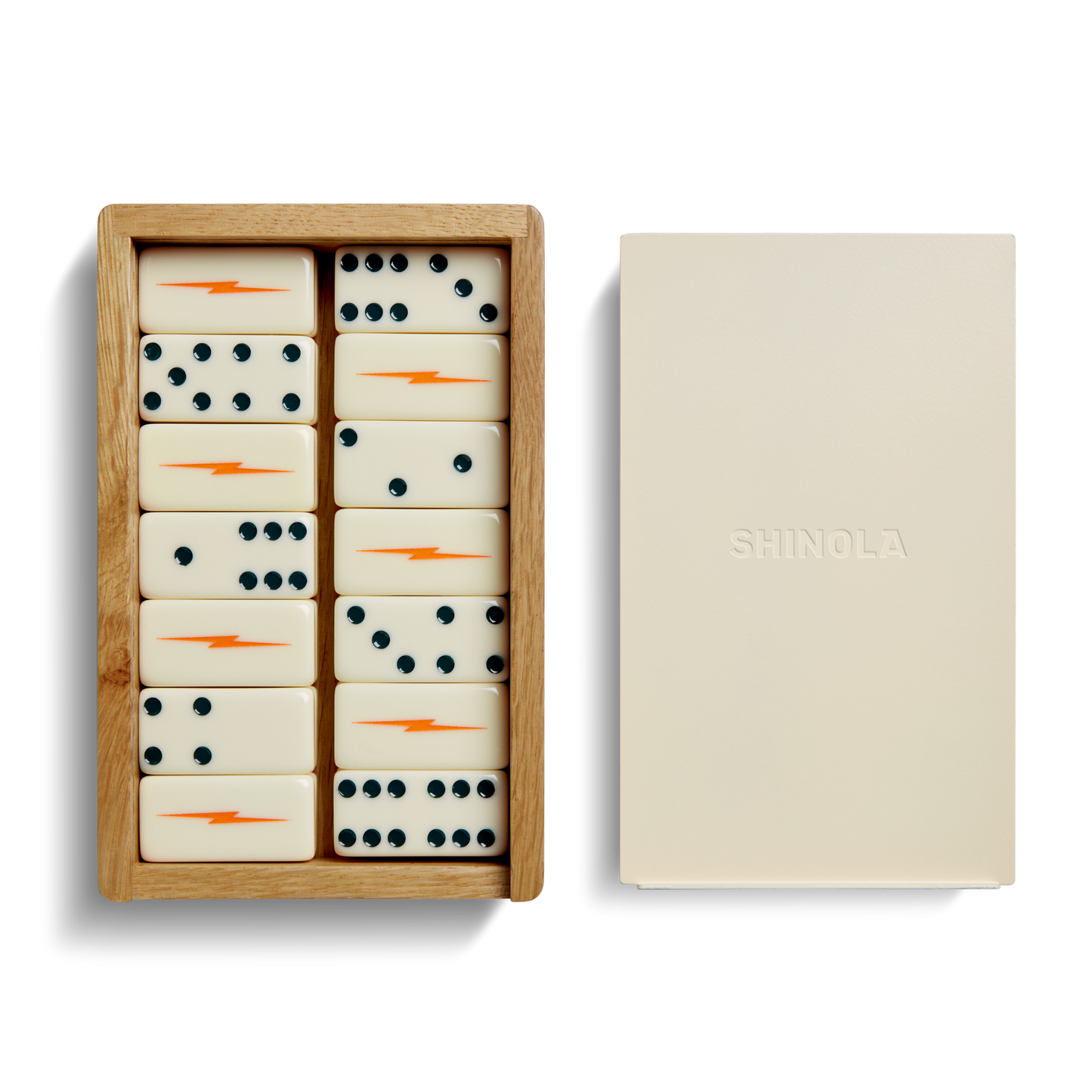 The Shinola Dominoes Set—Cream / Blue includes hand-painted cream tiles with blue dots and orange lightning bolts, presented in a wooden box beside a cream lid embossed with the Shinola logo.