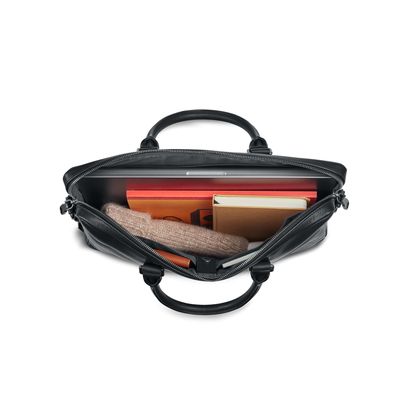 Top view of an open shinola-jp.computer Briefcase - Black holding a folded beige sweater, closed laptop, red folder, orange notebook, and yellow book against a white background.