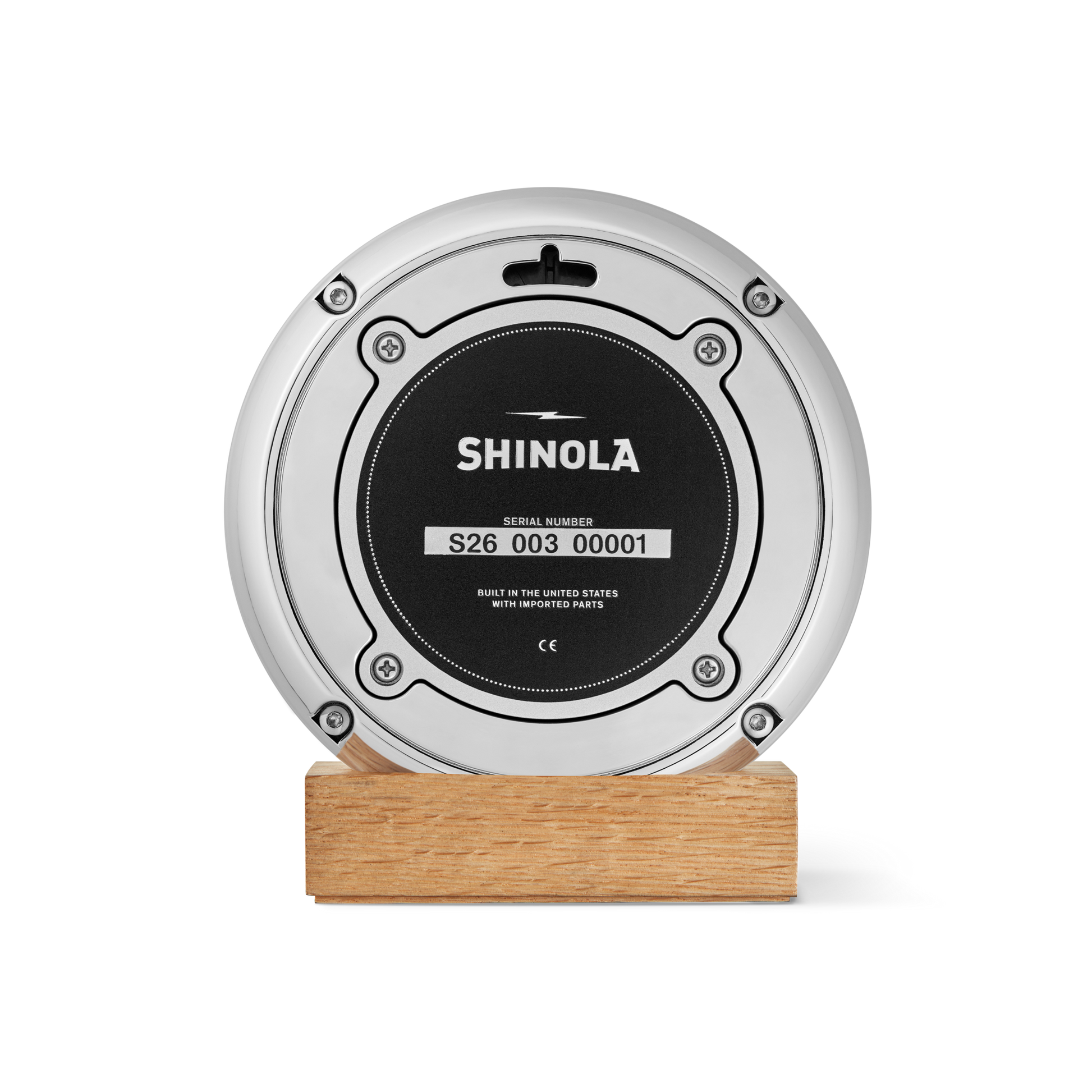 A round, silver Shinola 6" Runwell Clock with a green face, mounted on a rectangular wooden base, is photographed against a plain white background—crafted with precision at the Detroit watch factory.
