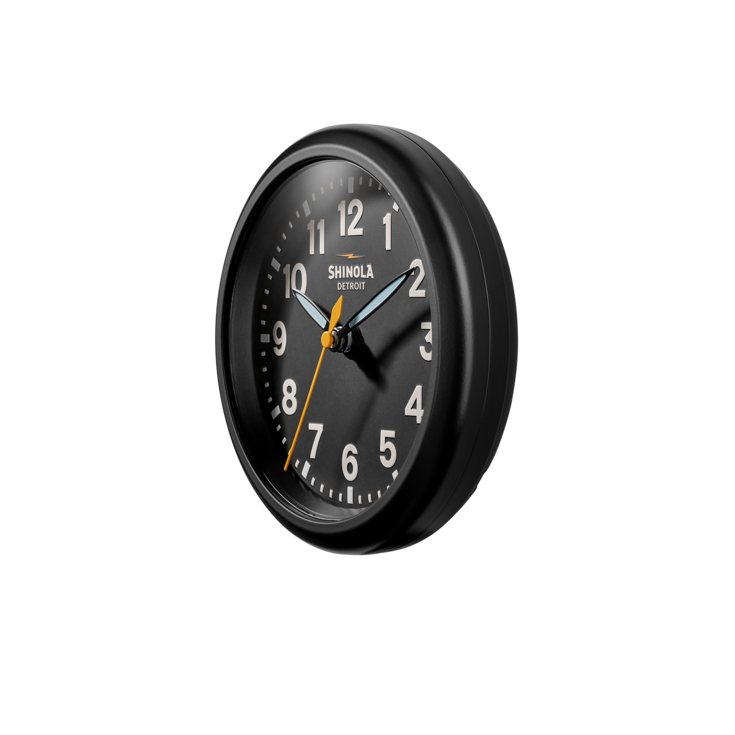 The Shinola 6" Runwell Clock in black features a round face with white numbers and hands, a yellow second hand, and is shown against a white background. The time displayed is 10:09:34.