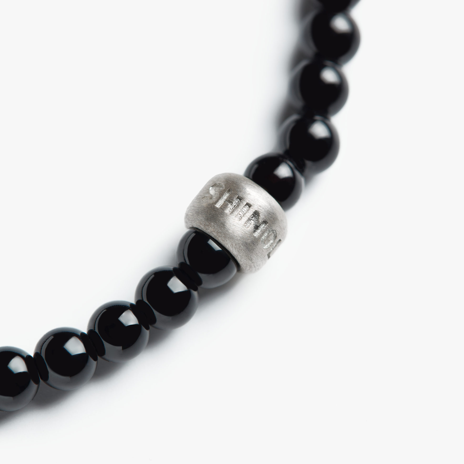 A close-up of the Shinola 4mm Beaded Onyx Bracelet, featuring onyx beads and a single sterling silver accent bead with engraved text, photographed against a white background.