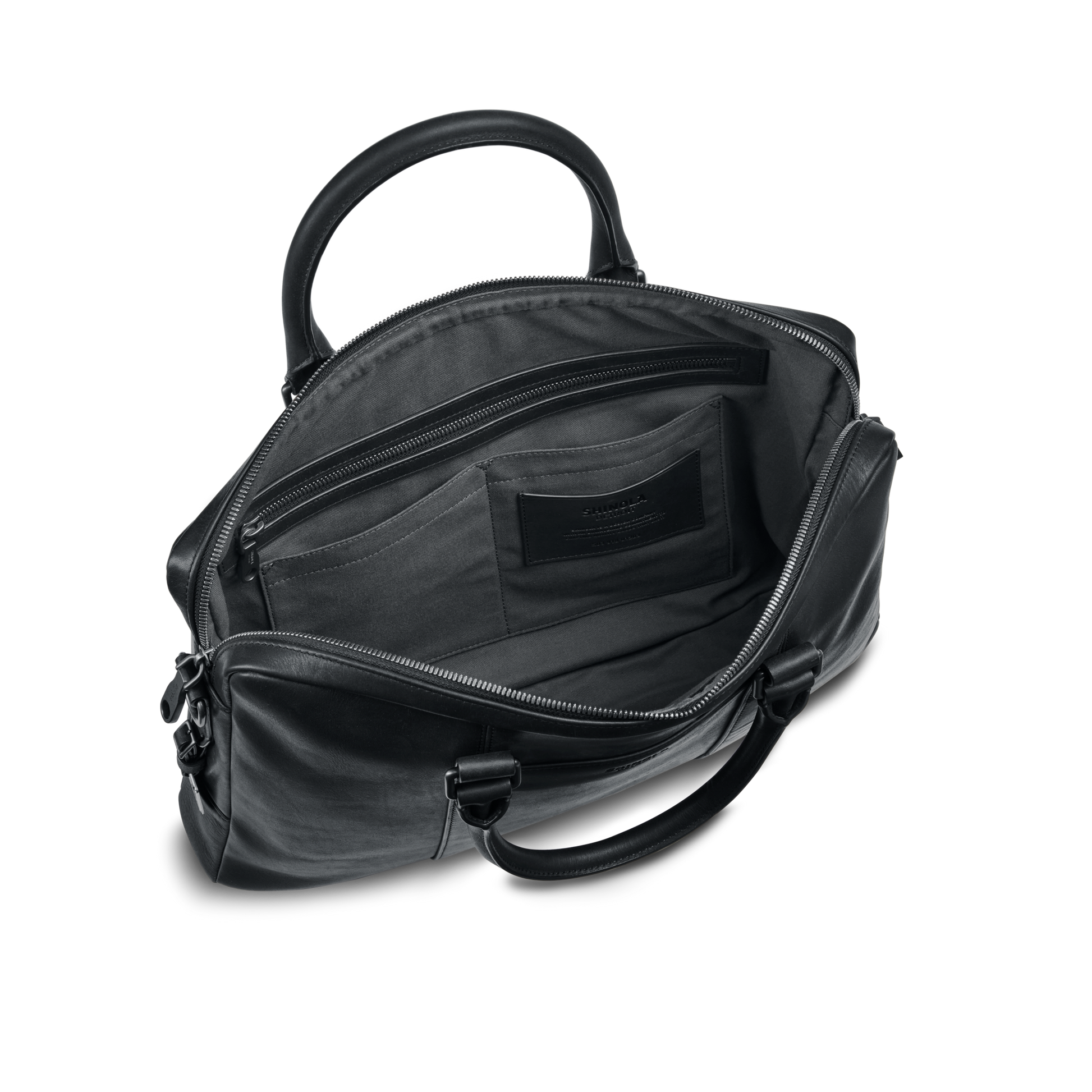 The shinola-jp.computer Briefcase - Black is shown open, displaying its spacious interior with multiple pockets. Featuring silver zippers, two sturdy handles, and a sleek modern design, it’s ideal as a stylish work bag.