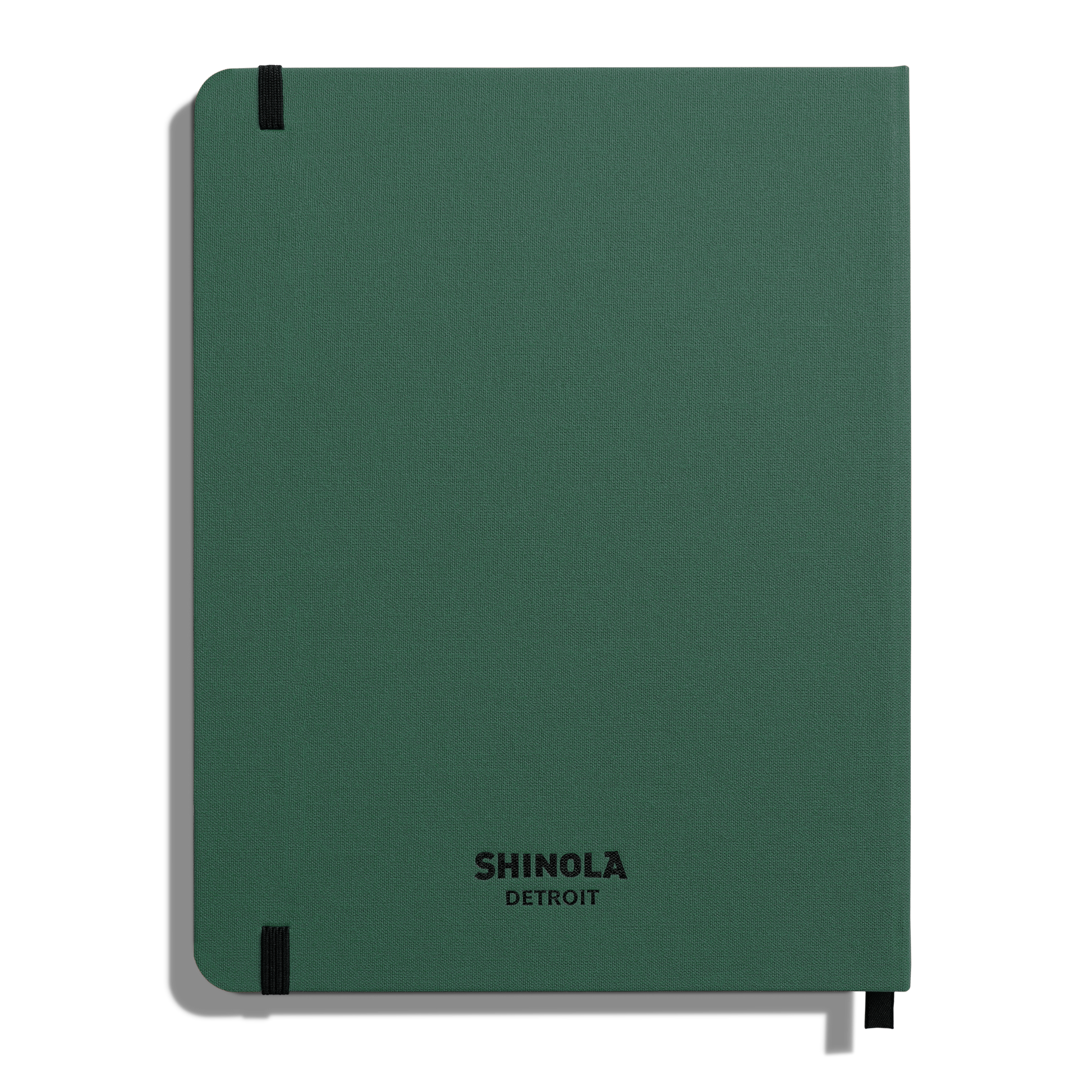 The Shinola Large Hard Ruled Journal – Fern is a green hardcover notebook with black elastic bands on the top left and bottom right. It features acid-free paper, and SHINOLA DETROIT is printed in black at the bottom center of the linen cover.