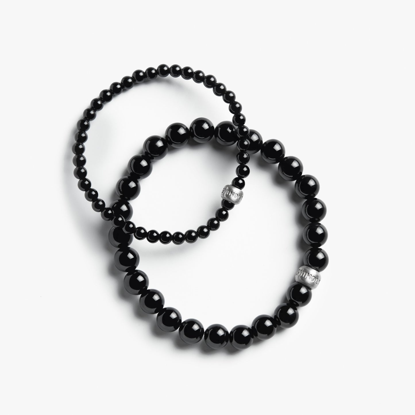 Two Shinola 4mm Beaded Onyx Bracelets, featuring sterling silver accent beads and glossy black onyx stones—one with larger and one with smaller beads—are displayed overlapping on a white background.