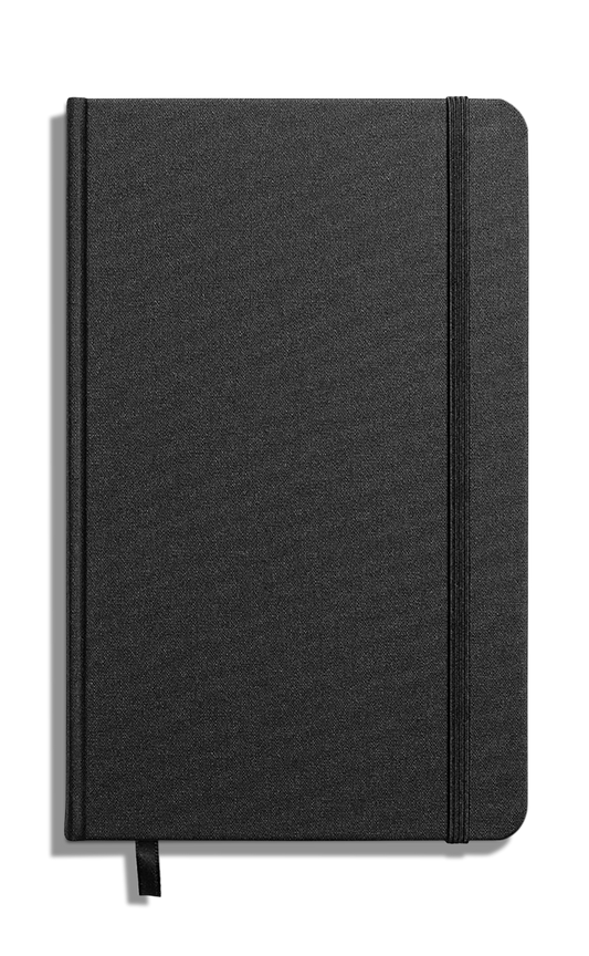 The Shinola Medium Hard Ruled Journal in black features a closed hardcover, Smyth-sewn binding, an elastic band on the right edge, and a black ribbon bookmark, all set against a white background.