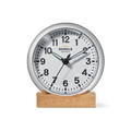 The 6" Runwell Clock - White by Shinola features a round white face, black numbers and hands, and sits on a wooden base; made in Detroit, it displays about 1:38:35 with Shinola branding on its face.